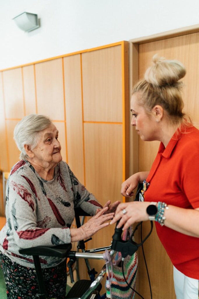 Caregiver Talking to a Senior Woman in a Corridor